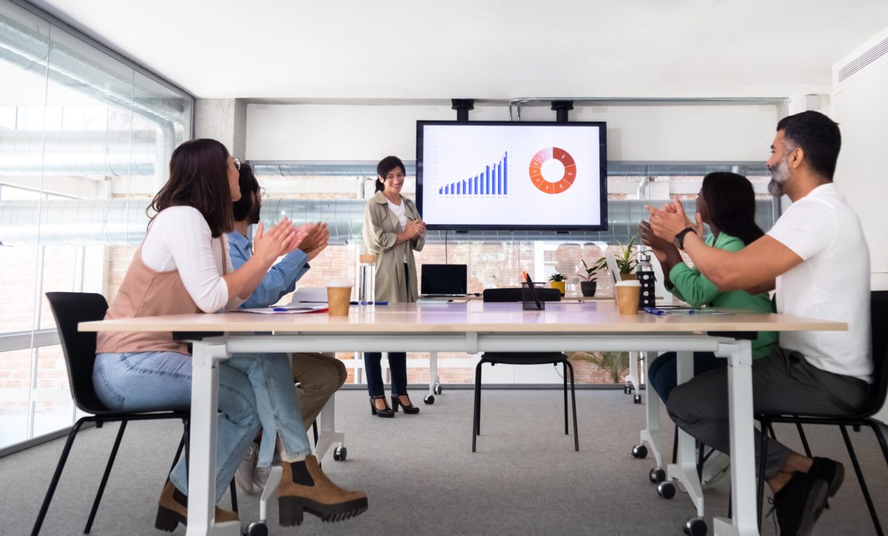 Group of multiracial coworkers celebrate great company result applauding together.